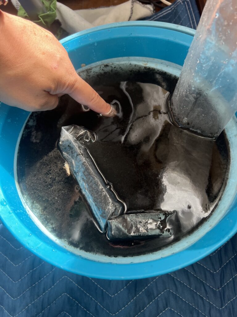 エアコン洗浄で出た黒い排水がバケツに溜まっている